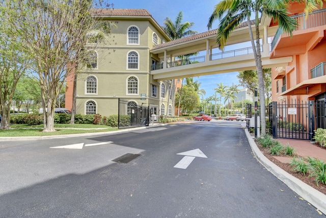 view of road featuring a gate, sidewalks, curbs, and a gated entry