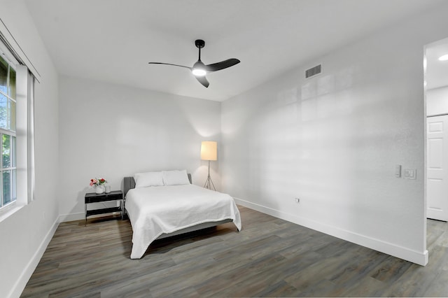 bedroom with a ceiling fan, baseboards, visible vents, and wood finished floors