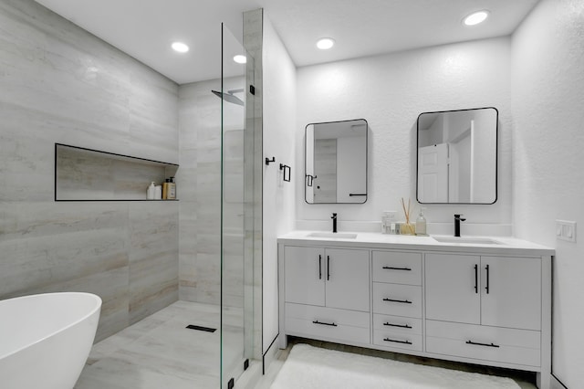 full bath featuring double vanity, a tile shower, and a sink