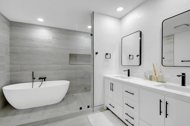 bathroom featuring a stall shower, a freestanding tub, a sink, and double vanity