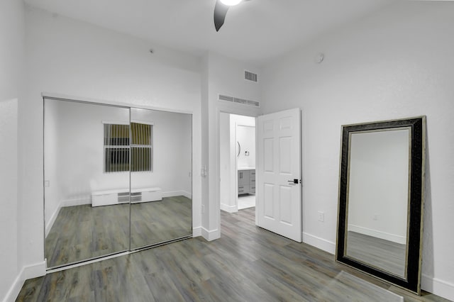 unfurnished bedroom featuring a closet, wood finished floors, visible vents, and baseboards