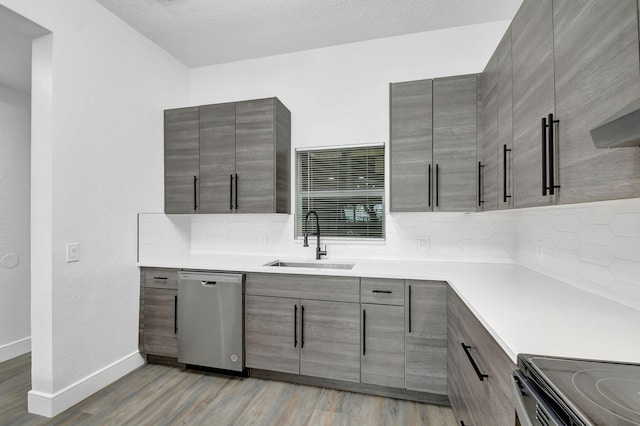 kitchen featuring dishwasher, light countertops, backsplash, and a sink