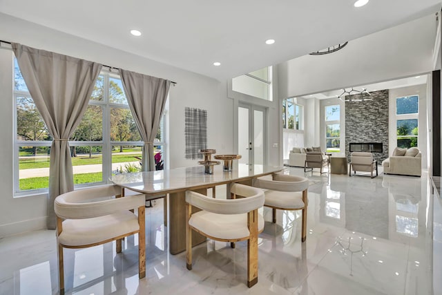 dining area featuring french doors, a stone fireplace, and a wealth of natural light