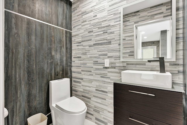 bathroom featuring vanity, toilet, and tile walls