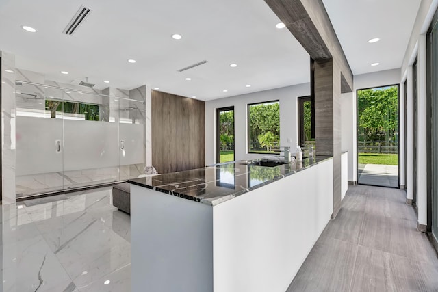 kitchen featuring white cabinetry, sink, dark stone counters, and kitchen peninsula