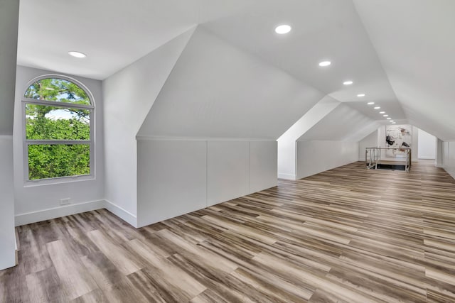 additional living space featuring vaulted ceiling and light hardwood / wood-style floors