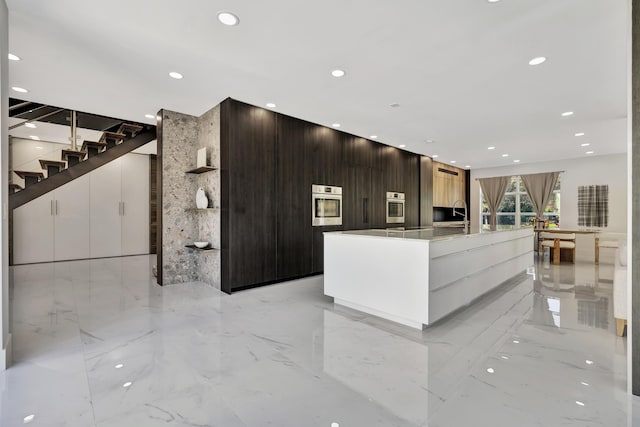 kitchen with a spacious island, oven, dark brown cabinets, and white cabinets