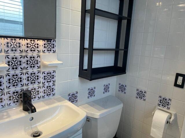 bathroom featuring toilet, sink, and tile walls