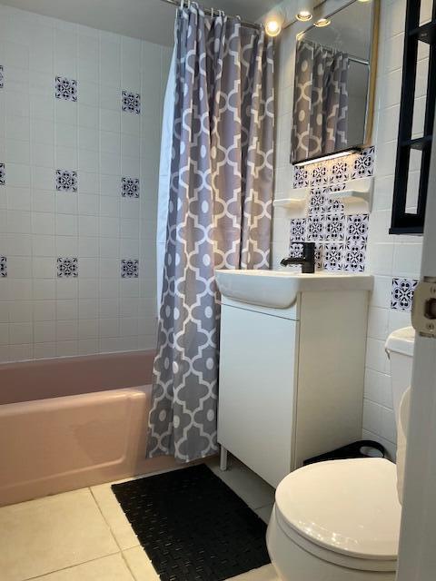 full bathroom featuring sink, shower / tub combo, tile patterned flooring, tile walls, and toilet