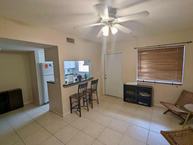 kitchen featuring ceiling fan, a textured ceiling, white fridge, and light tile patterned floors