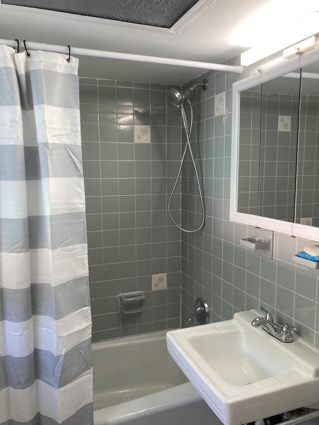 bathroom with shower / tub combo, sink, tasteful backsplash, and tile walls