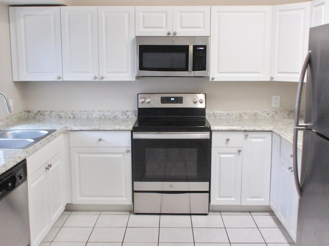 kitchen with light tile patterned flooring, sink, appliances with stainless steel finishes, light stone countertops, and white cabinets