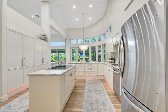 kitchen featuring light hardwood / wood-style flooring, white cabinetry, hanging light fixtures, stainless steel appliances, and kitchen peninsula