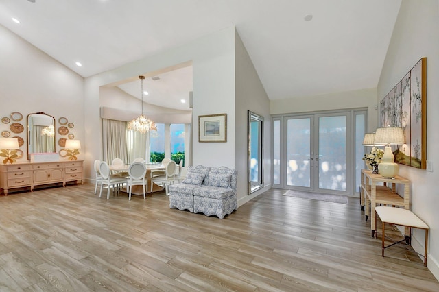 living area featuring french doors, a notable chandelier, high vaulted ceiling, and light hardwood / wood-style flooring