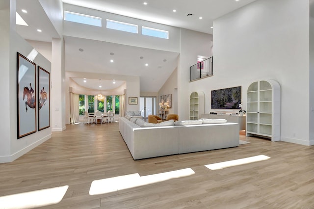 living room featuring a towering ceiling, light hardwood / wood-style floors, and a notable chandelier