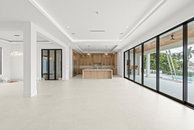 unfurnished living room with a raised ceiling and a notable chandelier