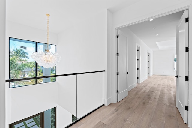 corridor featuring a notable chandelier and light hardwood / wood-style flooring