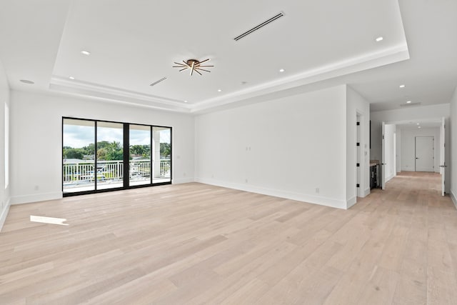 spare room with light hardwood / wood-style flooring and a tray ceiling