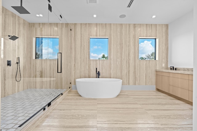 bathroom featuring plenty of natural light, plus walk in shower, and vanity