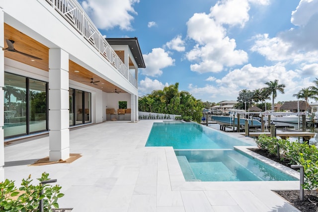 view of pool featuring a patio, a water view, a boat dock, and ceiling fan