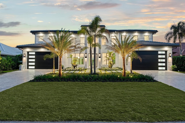 contemporary home featuring a garage and a lawn