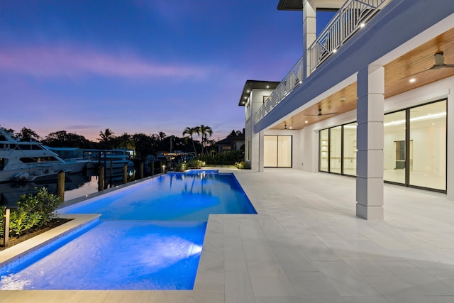 pool at dusk featuring a patio and ceiling fan