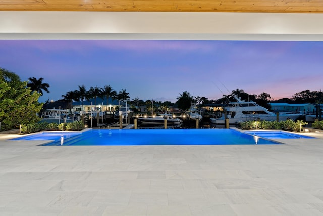 pool at dusk with a patio and a water view