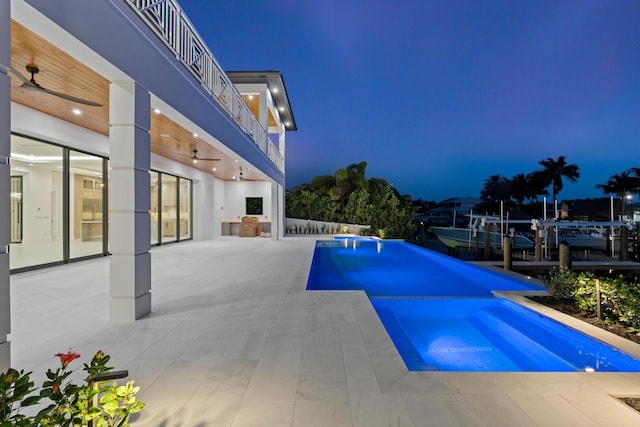 pool at dusk with a patio area, ceiling fan, and an in ground hot tub