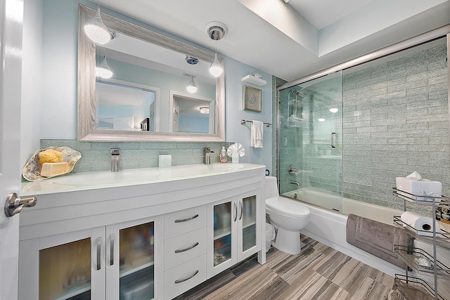 full bathroom featuring enclosed tub / shower combo, vanity, backsplash, and toilet