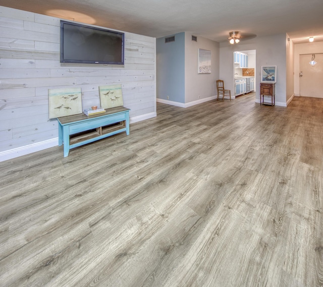 unfurnished living room with wood-type flooring and wooden walls