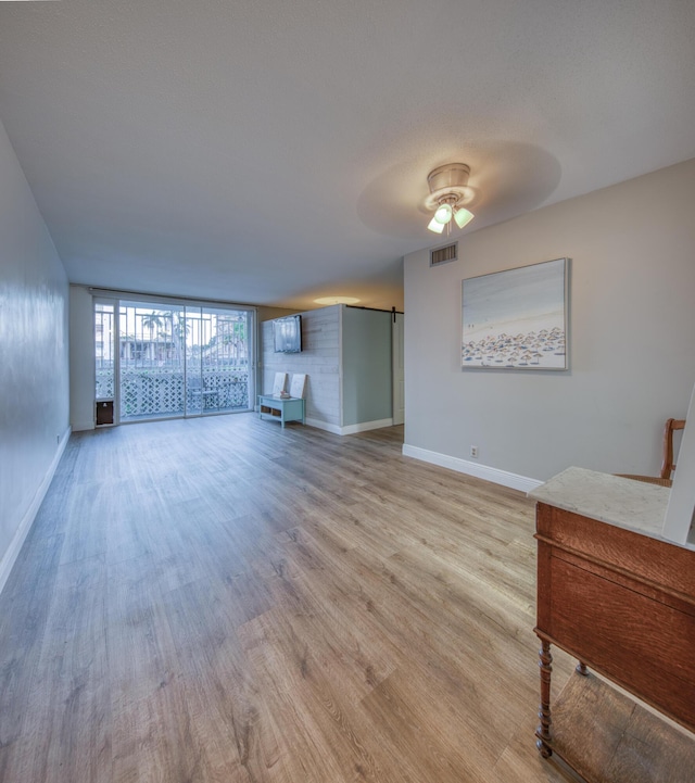1 S Lakeside Dr Unit A2, Lake Worth Beach, FL 33460 - unfurnished living room featuring light wood-type flooring, baseboards, a ceiling fan, and a barn door