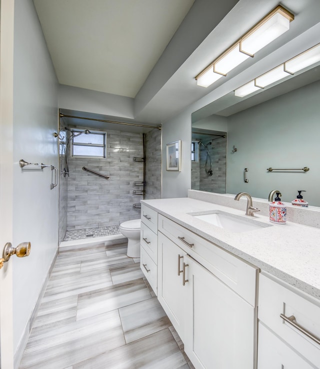 bathroom with tiled shower, vanity, and toilet