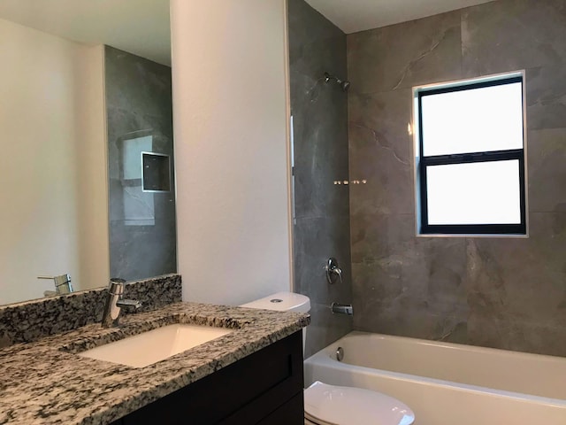 full bathroom with vanity, tiled shower / bath combo, and toilet