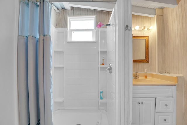 bathroom featuring vanity, a shower with shower curtain, and wood walls