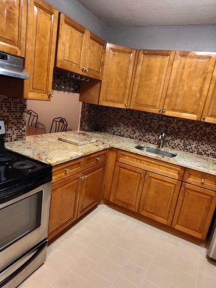 kitchen with electric stove, a sink, and brown cabinets