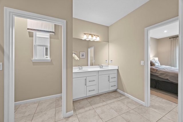 ensuite bathroom featuring double vanity, connected bathroom, a sink, tile patterned flooring, and baseboards