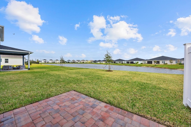 view of yard featuring a water view, a patio area, and a residential view