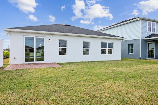 rear view of house featuring stucco siding, a shingled roof, a patio, and a yard