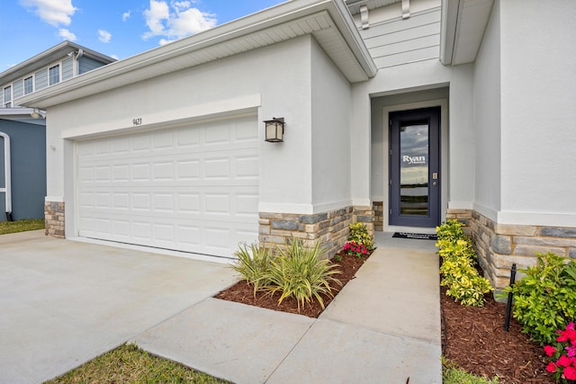 property entrance with an attached garage, stone siding, concrete driveway, and stucco siding