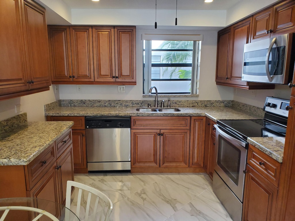 kitchen featuring light stone counters, stainless steel appliances, and sink