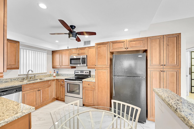 kitchen with light stone counters, ceiling fan, appliances with stainless steel finishes, and sink