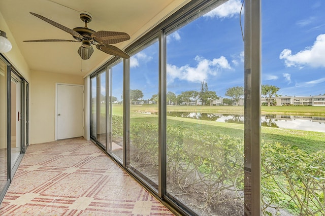 unfurnished sunroom featuring a water view and ceiling fan