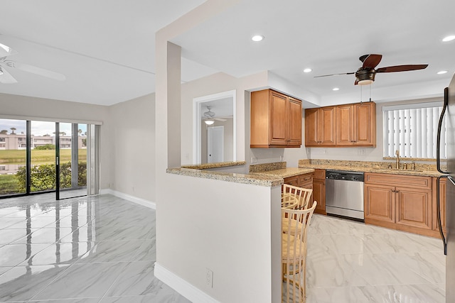 kitchen with ceiling fan, light stone counters, marble finish floor, stainless steel dishwasher, and a sink