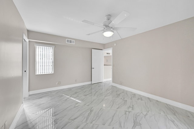 spare room with marble finish floor, visible vents, ceiling fan, and baseboards