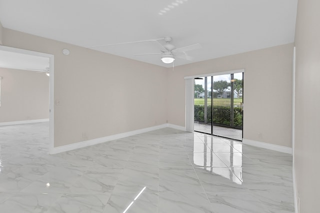 spare room with marble finish floor, a ceiling fan, and baseboards