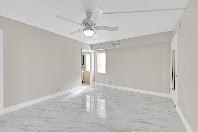 empty room featuring marble finish floor, visible vents, ceiling fan, and baseboards