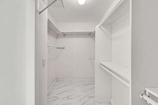 walk in closet featuring marble finish floor