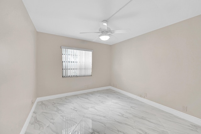 spare room with ceiling fan, marble finish floor, and baseboards