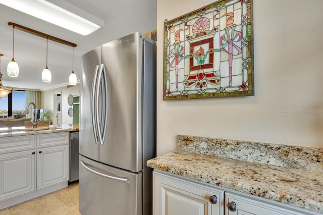 kitchen featuring a sink, decorative light fixtures, white cabinetry, stainless steel appliances, and light stone countertops