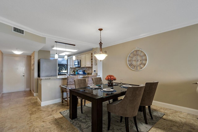 dining area with crown molding and sink